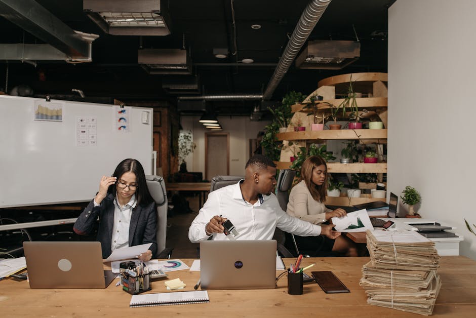 Diverse team collaborating in a modern office setting with laptops and documents