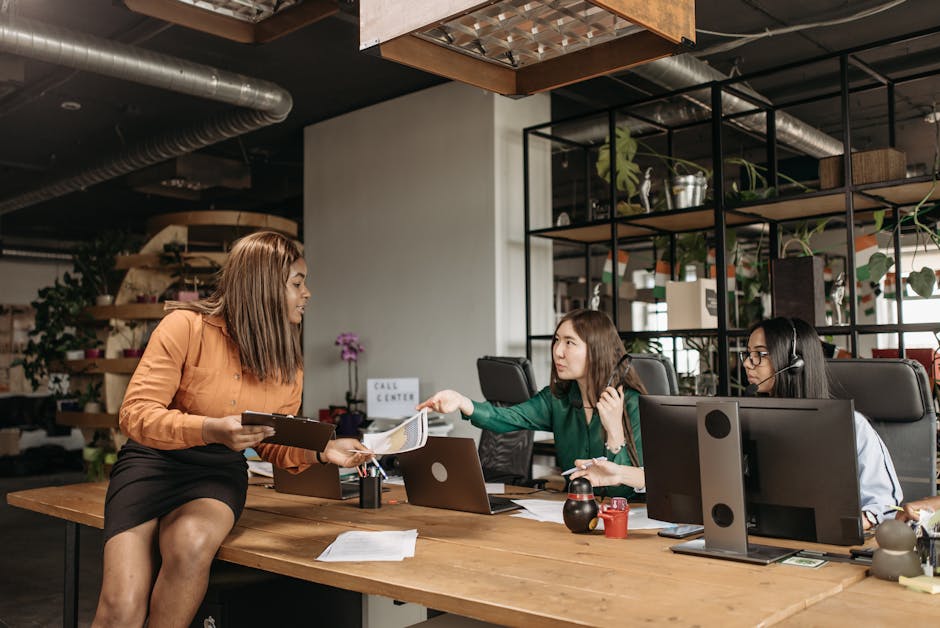 Diverse group of female professionals discussing work at their desk in a modern office setting